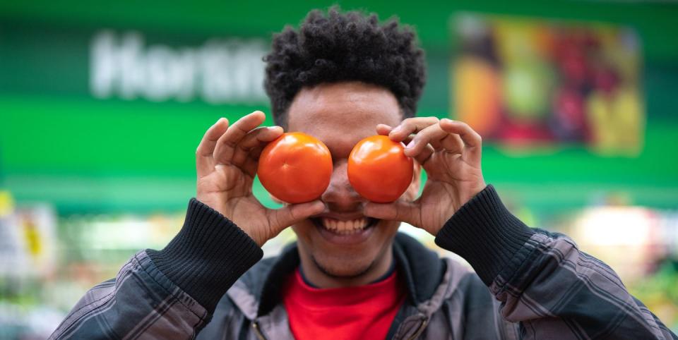 un hombre juega con dos tomates en el supermercado