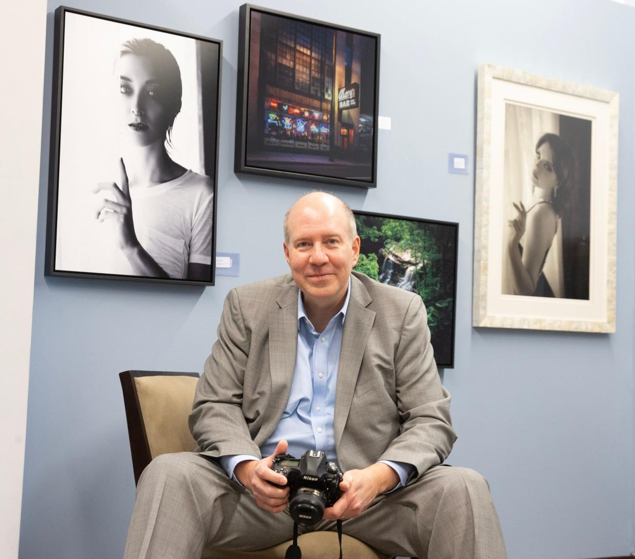 Photographer David Dingwell sits near some of his work at Patina Arts Centre in downtown Canton. Dingwell and Melissa Goff will be presenting the joint art exhibition "Coalescence" at the gallery from 5 to 9 p.m. Friday.