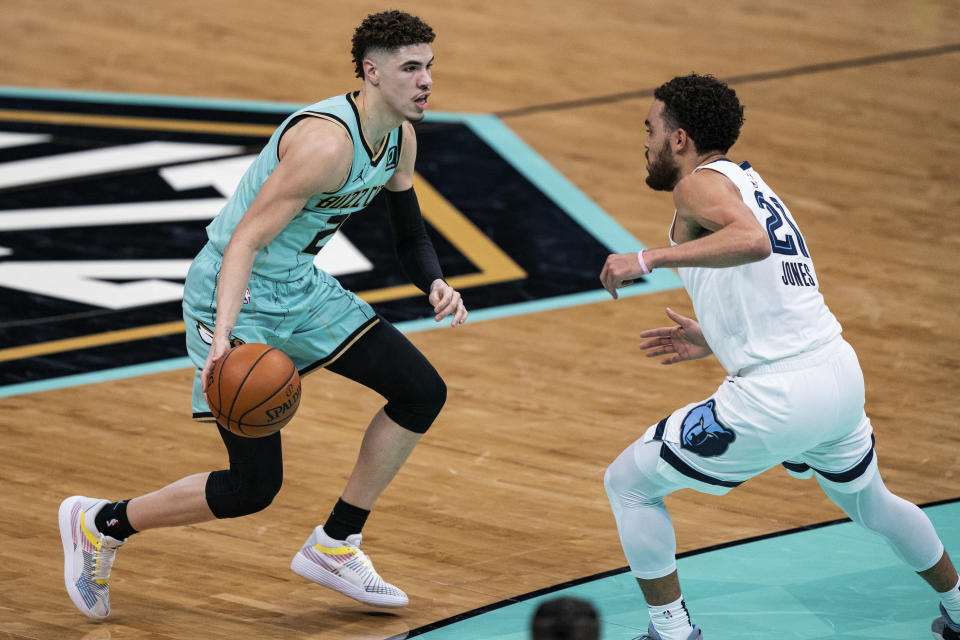 Charlotte Hornets guard LaMelo Ball (2) is defended by Memphis Grizzlies guard Tyus Jones (21) during the first half of an NBA basketball game in Charlotte, N.C., Friday, Jan. 1, 2021. (AP Photo/Jacob Kupferman)