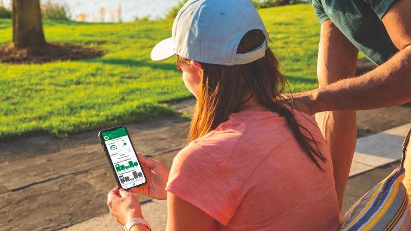 A user accessing the John Deere MowerPlus mobile app on their smartphone.