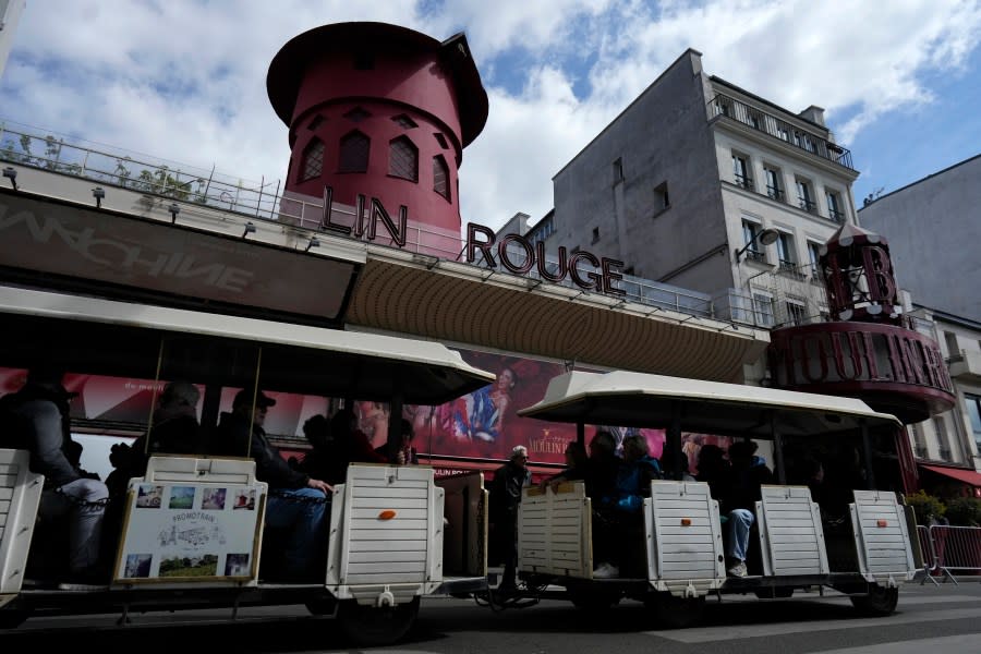 A tourists train drives past the Moulin Rouge (Red Mill) Thursday, April 25, 2024 in Paris. The windmill from the Moulin Rouge, the 19th century Parisian cabaret, has fallen off the roof overnight along with some of the letters in its name. (AP Photo/Thibault Camus)