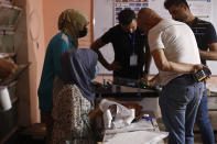 Employees of the Independent High Electoral Commission close a polling station at the end of voting in parliamentary elections, in Baghdad, Iraq, Sunday, Oct. 10, 2021. Iraq closed its airspace and land border crossings on Sunday as voters headed to the polls to elect a parliament that many hope will deliver much needed reforms after decades of conflict and mismanagement. (AP Photo/Hadi Mizban)