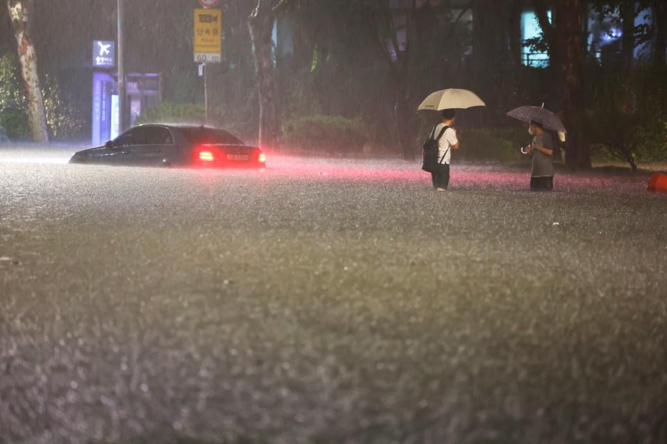 A vehicle is submerged in a flooded road in Seoul (AP)