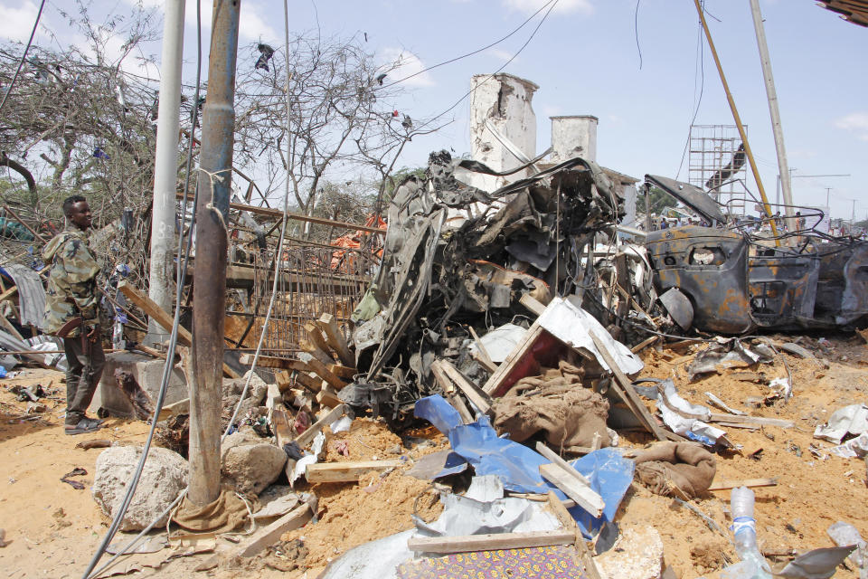 Un soldado monta guardia junto a los restos de vehículos e inmuebles dañados por el estallido de un camión bomba en Mogadiscio, Somalia, el sábado 28 de diciembre de 2019. (AP Foto/Farah Abdi Warsame)