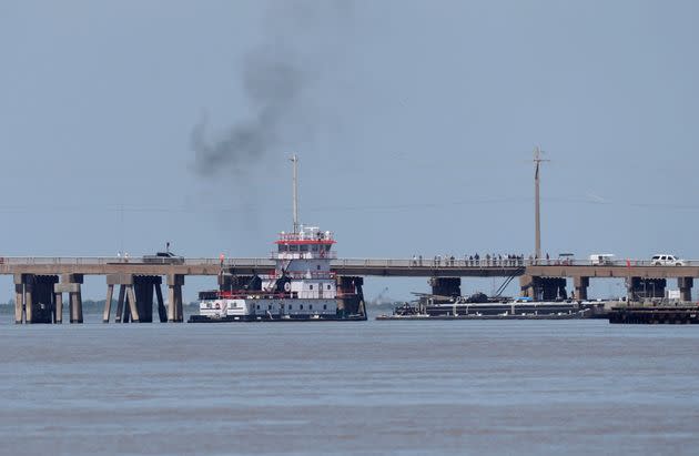 A tugboat works to maneuver a barge away from the Pelican Island Bridge in Galveston, Texas.