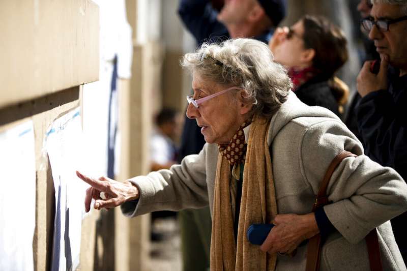 阿根廷11日舉行總統初選，一位老太太聚精會神地看著選舉公報。（美聯社）