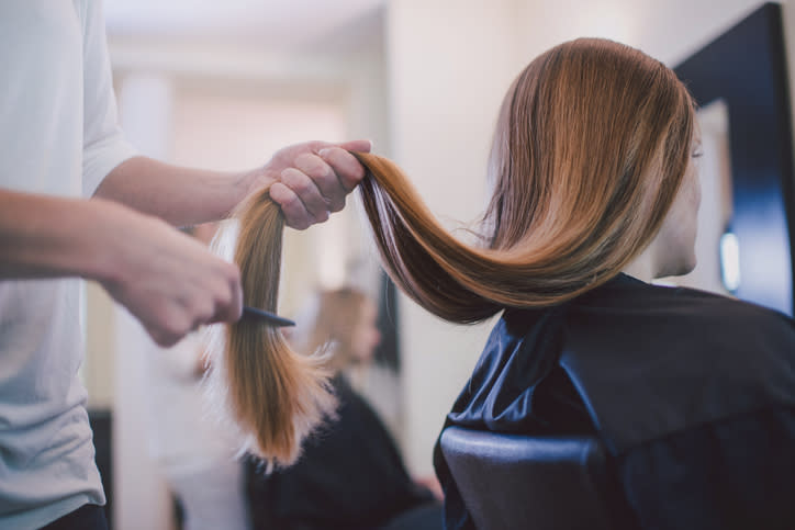 Hairdresser trimming the ends of a client's straight hair in a salon