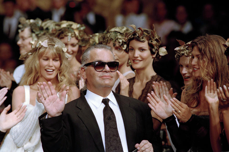 En esta foto del 20 de julio de 1993, el diseñador alemán Karl Lagerfeld agradece el aplauso de sus modelos al final de un desfile de la casa Chanel en París. El emblemático modisto murió el martes 19 de febrero del 2019. Tenía alrededor de 85 años. (AP Foto/Lionel Cironneau, Archivo)