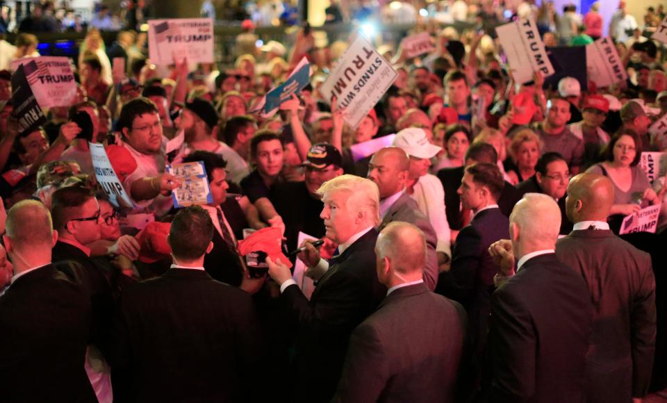 Flanked by members of the Secret Service, Republican presidential candidate Donald Trump, center, signs for supporters as stage lights paint the dance floor following an appearance on June 16, 2016 at Gilley's in Dallas, Texas. Trump arrived in Texas on Thursday with plans to hold rallies and fundraisers.