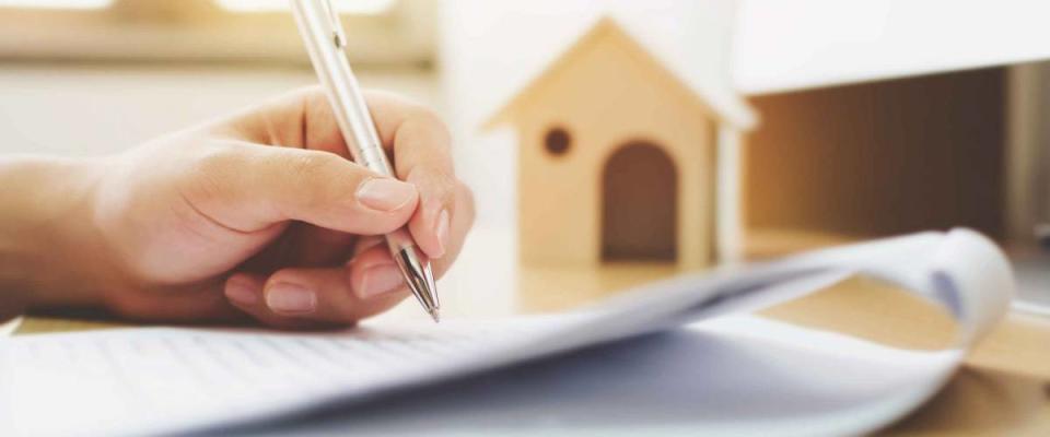 Close up hand of man signing signature loan document to home ownership. Mortgage and real estate property investment