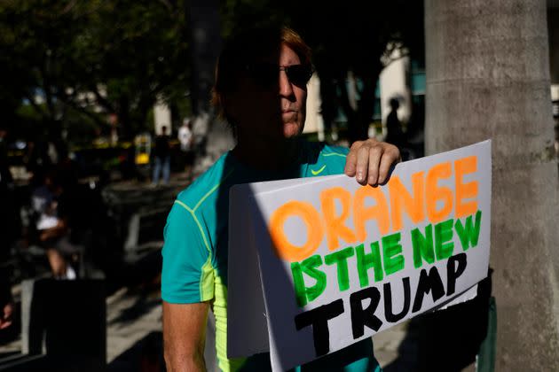 A man holds a sign outside the courthouse reading 