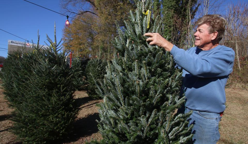 Lot manager John Mostinger sets out trees for sale at Santa’s Christmas Tree lot near the intersection of Wilkinson Blvd. and Wesleyan Drive near McAdenville Tuesday afternoon, Nov. 30, 2021.