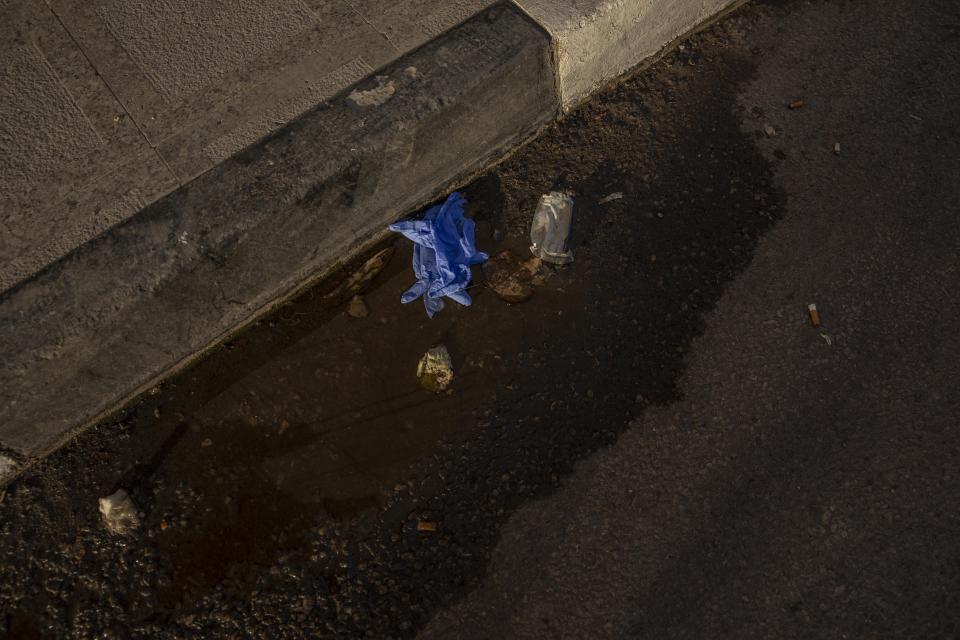 FILE - This April 3, 2020 file photo, shows used medical gloves thrown on a street in Cairo, Egypt. Coronavirus infections are surging in the country of 100 million, threatening to overwhelm hospitals. (AP Photo/Nariman El-Mofty, File)