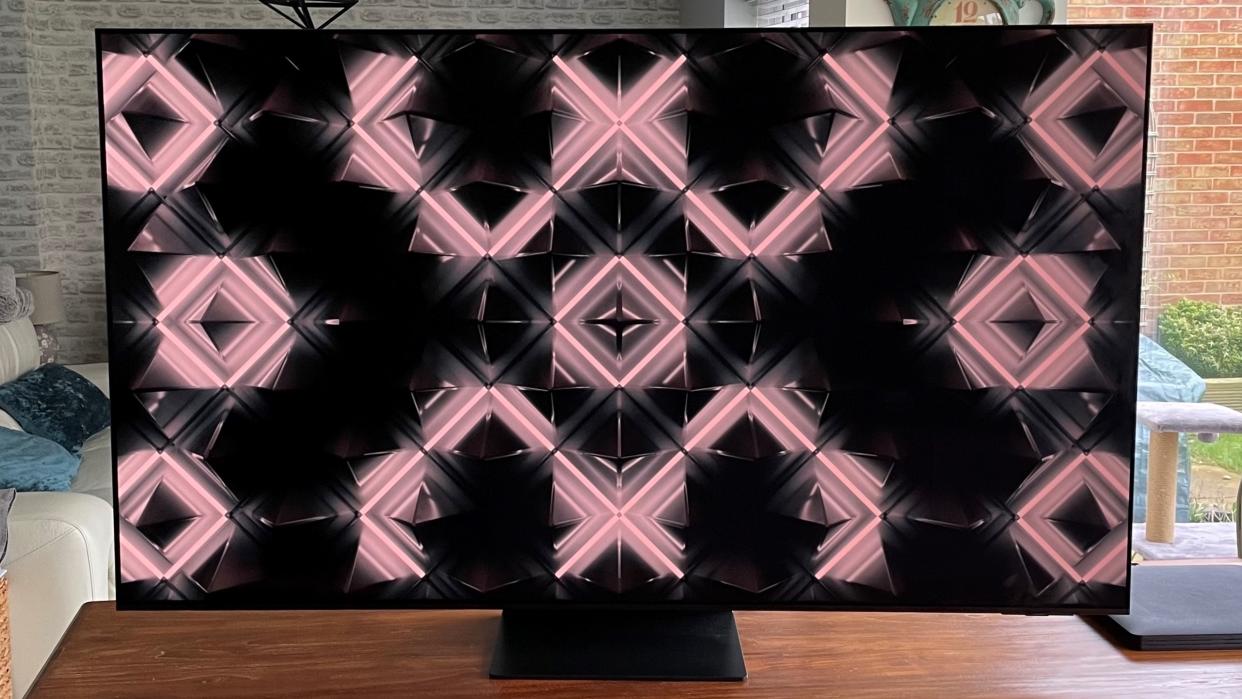  Samsung S95C OLED TV showing abstract image on wood table. 