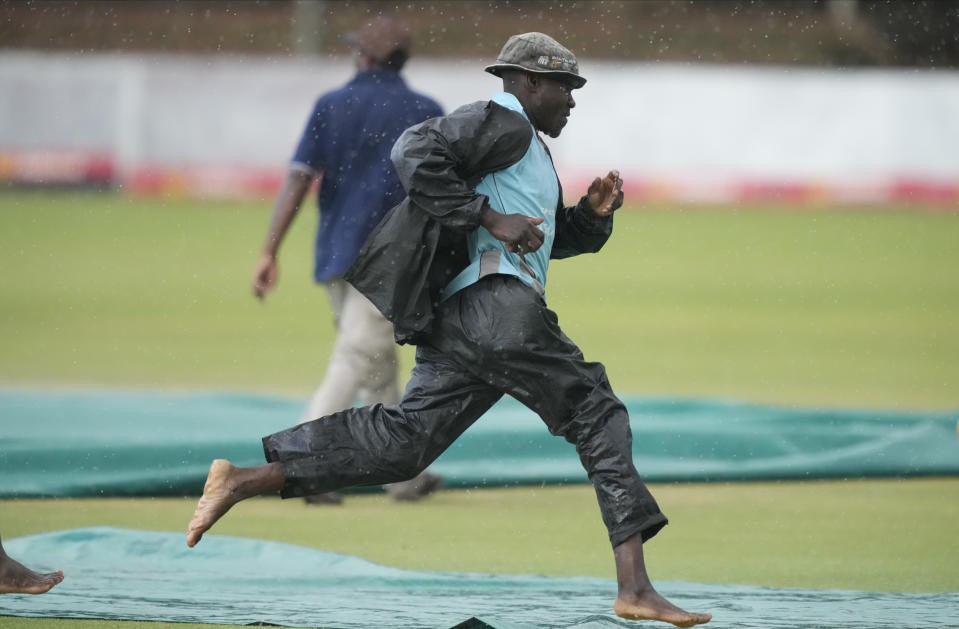 Groundsmen rush to cover the pitch following rain on the second day of the second Test cricket match between Zimbabwe and West Indies at Queens Sports Club in Bulawayo, Zimbabwe, Monday,Feb, 13, 2023. (AP Photo/Tsvangirayi Mukwazhi)