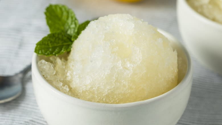 Close-up of a bowl of lemon Italian ice in a bowl with a mint garnish