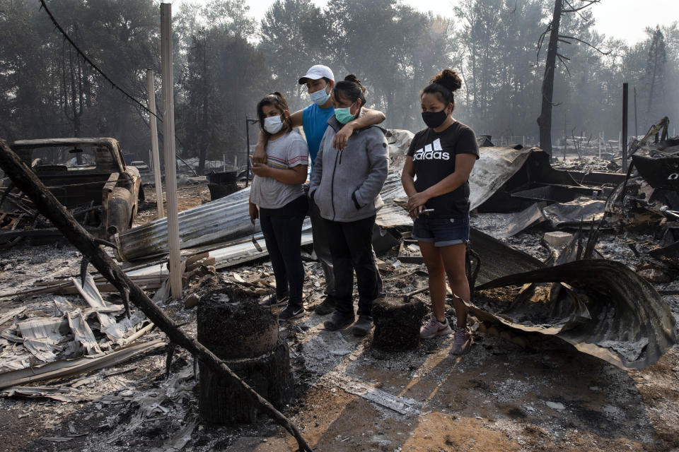 The Reyes family looks at the destruction of their home at Coleman Creek Estates mobile home park in Phoenix, Ore., Thursday, Sept. 10, 2020. The area was destroyed when a wildfire swept through on Tuesday, Sept. 8. (AP Photo/Paula Bronstein)