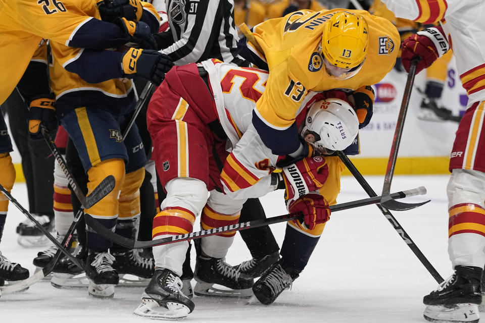 Nashville Predators center Yakov Trenin (13) fights with Calgary Flames defenseman MacKenzie Weegar (52) during the second period of an NHL hockey game Thursday, Jan. 4, 2024, in Nashville, Tenn. (AP Photo/George Walker IV)