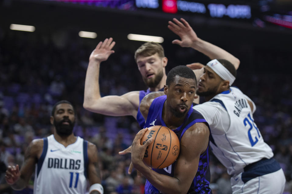 Sacramento Kings forward Harrison Barnes (40) grabs a rebound in front of Dallas Mavericks center Daniel Gafford (21) and forward Domantas Sabonis in the first half of an NBA basketball game in Sacramento, Calif., Tuesday, March 26, 2024. (AP Photo/José Luis Villegas)