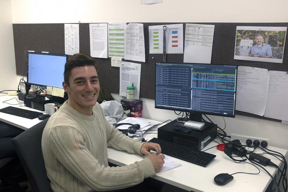 Pictured is James Kondilios sitting at a computer. He was a data scientist and powerlifter.