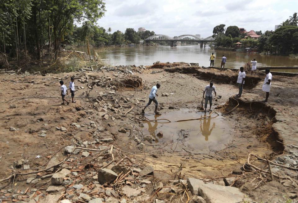 <p>Männer am Stadtrand von Kochi im indischen Kerala begutachten den Schaden, den die Flutkatastrophe in der Stadt angerichtet hat. Rund 200 Menschen starben durch die Flut, 800.000 mussten fliehen. (Bild: AP Photo/Aijaz Rahi) </p>