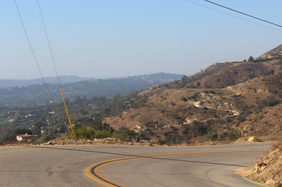 Hazy-smoke skies, with wooded Montecito on left and a cleared out high road driveway on right.