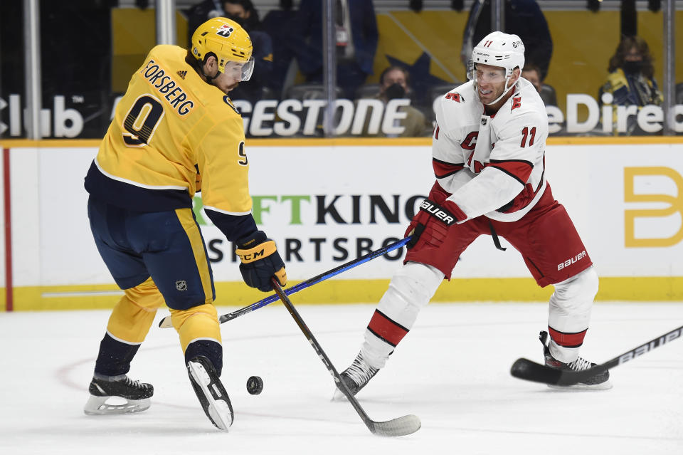 Nashville Predators left wing Filip Forsberg (9) blocks a shot by Carolina Hurricanes center Jordan Staal (11) during the first period of an NHL hockey game Saturday, May 8, 2021, in Nashville, Tenn. (AP Photo/Mark Zaleski)