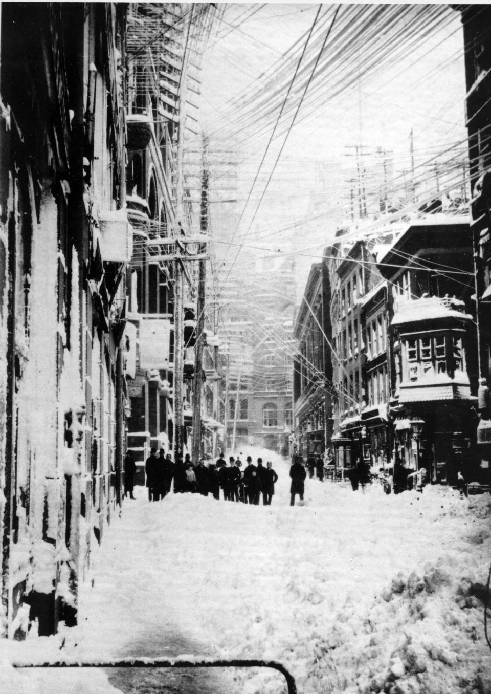 A New York street is shown during the blizzard of 1888.  The blizzard that occured March 12-14 paralyzed the city with 40" of snow and winds that reached up to 60 miles per hour, creating drifts as high as 50 feet.  Telegraph and telephone poles and wires were downed and lay in the streets.  