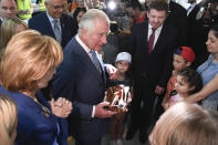 Britain's Prince Charles and Princess Margaret, the Custodian of the Romanian Crown, offer presents to refugees during a visit at a center for refugees fleeing the war in neighboring Ukraine, at the Romexpo convention center, in Bucharest, Romania, Wednesday, May 25, 2022. (Alex Micsik/Pool via AP)