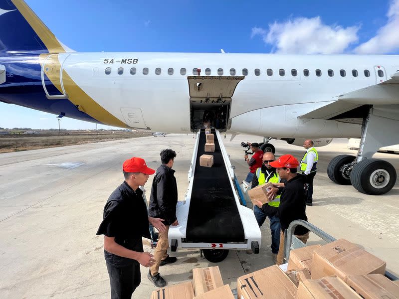 Members of Libya's Youth Hostels Association unload medical aid that arrived by plane at al Abraq airport