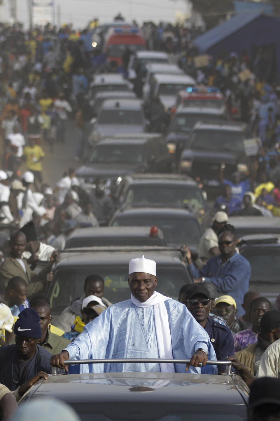 Senegalese President Abdoulaye Wade is surrounded by supporters and security as his convoy travels between campaign stops in downtrodden suburban neighborhoods of Dakar, Senegal Wednesday, Feb. 22, 2012. Thousands of supporters turned out to see Wade as he held rallies in the Pikine and Guediawaye neighborhoods on Wednesday. Daily protests have rocked the capital after the opposition vowed to render the country ungovernable if 85-year-old Wade runs for a third term in Sunday's elections.(AP Photo/Rebecca Blackwell)
