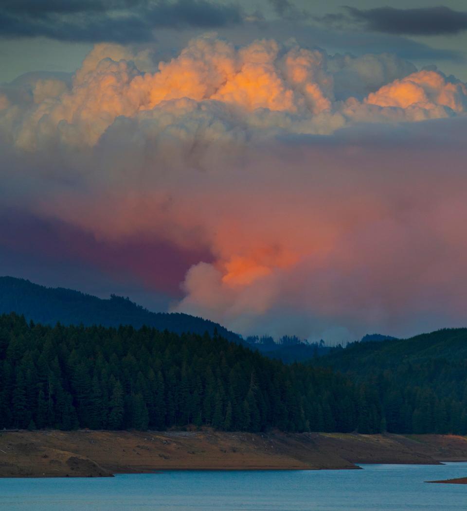 The sun sets as the Bedrock Fire sends up a plume of smoke above Fall Creek east of Eugene Monday, July 24, 2023.