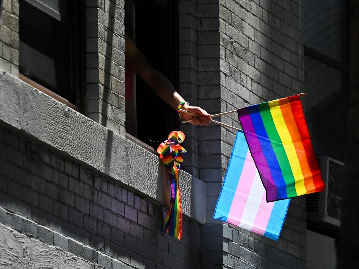 A person waves pride flags out a window during the New York City Pride Parade on June 26, 2022