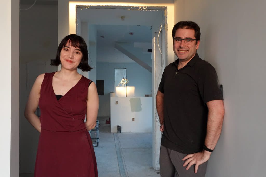 Two people smile in a home that is under construction. 