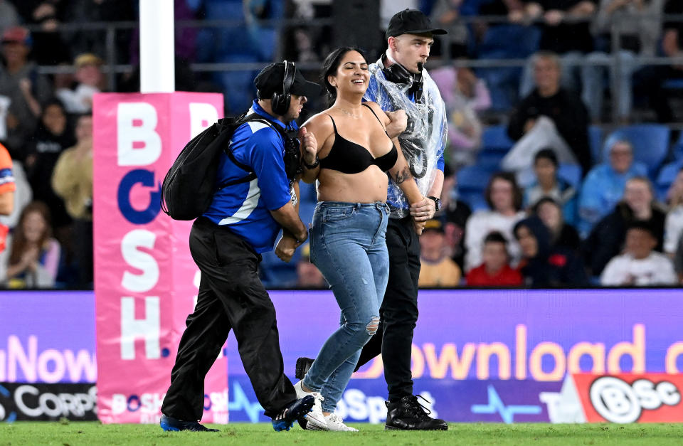 A pitch invader, pictured here being taken from the field by security guards.