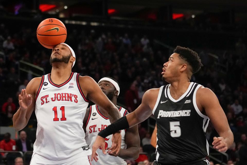 St. John's center Joel Soriano (11) tries to control a rebound as PC's Ed Croswell looks on during Saturday's game.