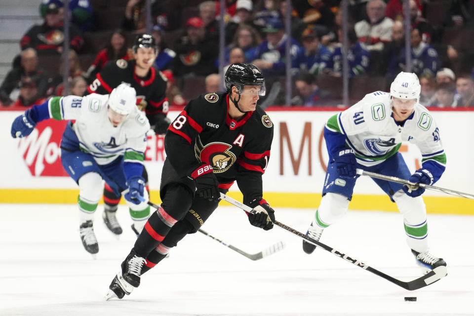 Ottawa Senators center Tim Stutzle (18) skates the puck up ice as Vancouver Canucks center Elias Pettersson (40) chases during the first period of an NHL hockey match in Ottawa, Ontario, on Thursday, Nov. 9, 2023. (Sean Kilpatrick/The Canadian Press via AP)