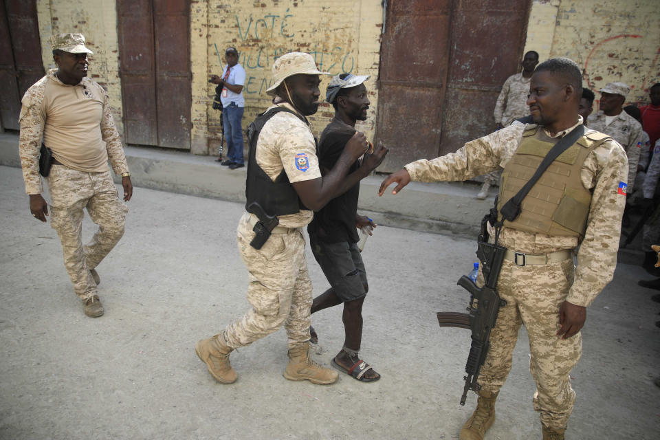 Police officers block a group of persons as they protest against the arrival of the USNS Comfort hospital ship in Jeremie, Haiti, Tuesday, Dec. 13, 2022. The USNS Comfort is on a humanitarian mission to provide dental and medical services. (AP Photo/Odelyn Joseph)