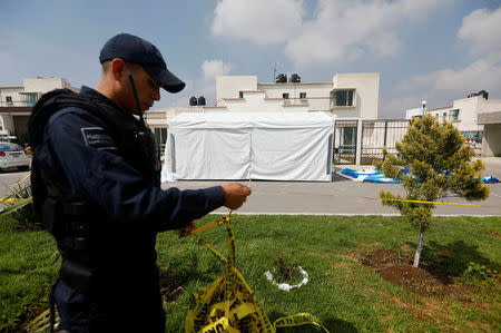 A police officer cordons off a crime scene outside of a house where eleven people were found dead at Villa de los Milagros residential park, in the city of Tizayuca in Mexican state of Hidalgo, Mexico, July 13, 2017. REUTERS/Edgard Garrido