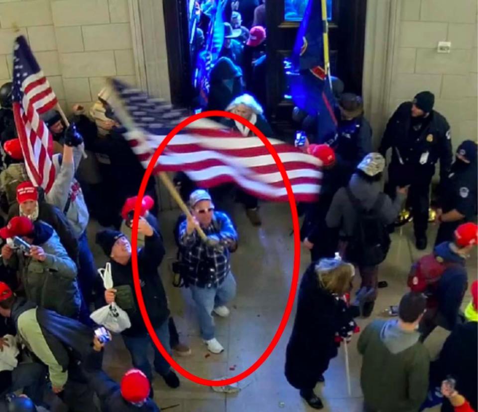 Jeremiah Powell, circled in red, is allegedly pictured here waving an American flag as officers close the East Front Doors behind Jan. 6, 2021.