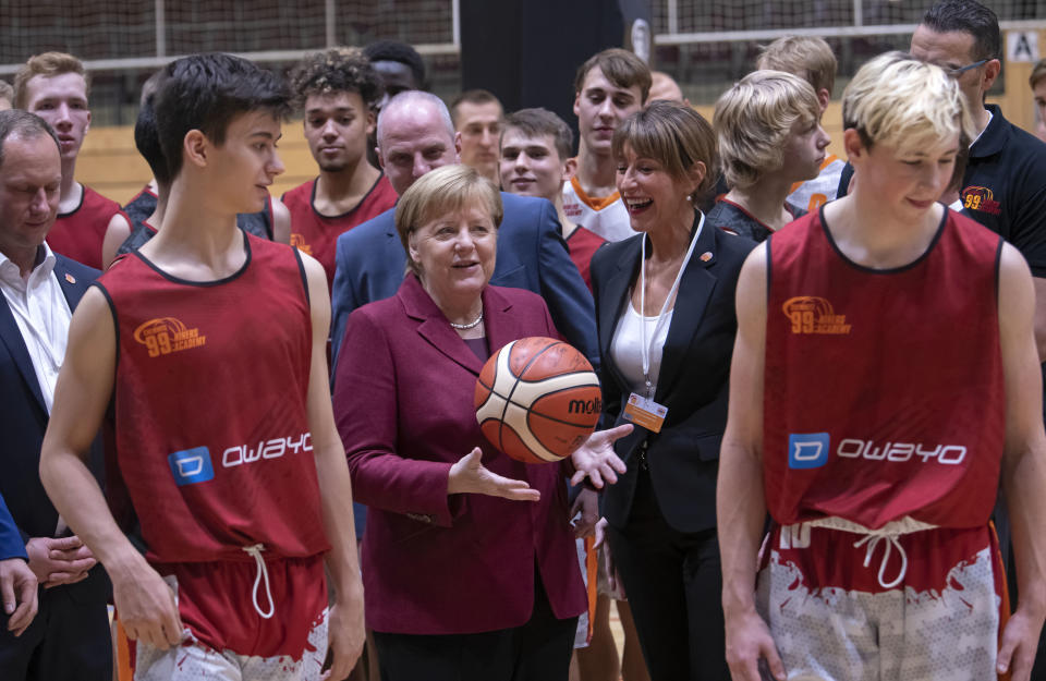 German Chancellor Angela Merkel, 3rd of left, throwes the ball besides Micaela Schoenherr, President of the NINERS, 3rd of right, and members of the NINERS German first divisioner basketball youth teams (under 16 years and under 19 years) during her one-day visit in Chemnitz, eastern Germany, Friday, Nov. 16, 2018. Chemnitz has seen a few federal politicians show their faces since a 35-year-old local man was stabbed to death in August, allegedly by migrants, followed by a surge of violent right-wing protests. (AP Photo/Jens Meyer)