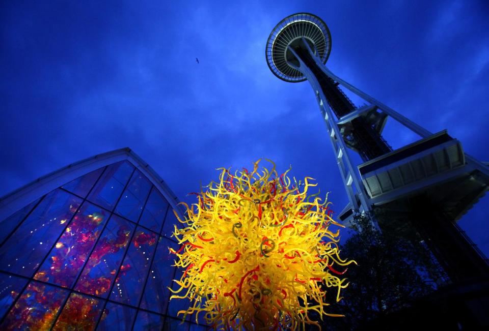 In this May 16, 2012 photo, the Space Needle towers over "The Sun," center, and the Glasshouse, left, at the new Dale Chihuly Garden and Glass museum at the Seattle Center. Fifty years after the World's Fair inserted the Space Needle into Seattle's skyline, the city is celebrating that anniversary by offering an array of new things to see and do at Seattle Center: from a zip line to the new art glass museum.(AP Photo/seattlepi.com, Joshua Trujillo) MAGS OUT; NO SALES; SEATTLE TIMES OUT; MANDATORY CREDIT; TV OUT