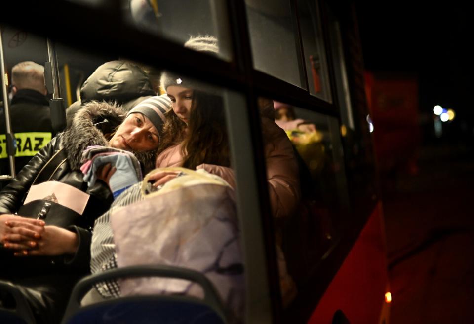 A woman leans against a child as they sit inside a bus