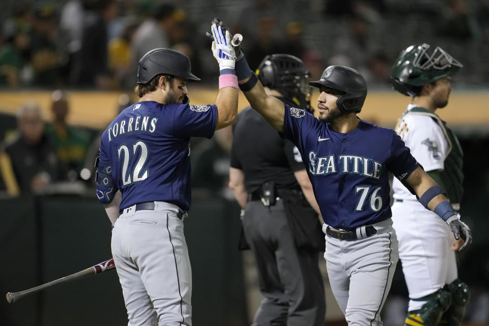 Seattle Mariners'n Jose Caballero (76) is congratulated by teammate Luis Torrens (22) after hitting a two-run home run that also scored Dylan Moore during the fourth inning of a baseball game against the Oakland Athletics in Oakland, Calif., Monday, Sept. 18, 2023. (AP Photo/Jeff Chiu)