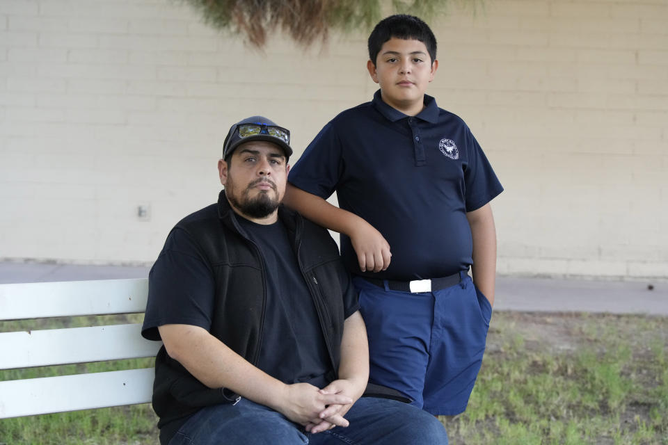 Aaron Galaz and his son pose for a photo on Wednesday, Oct. 18, 2023 in Phoenix. Aaron Galaz said his son is enrolled in a program that uses taxpayer funds to pay for private-school tuition in part so his son could be challenged more in class. At least four states that have made most children eligible for taxpayer-funded scholarships to private schools are seeing more families using the programs than planned. That could cost taxpayers, but it's early to know the exact budget implications. (AP Photo/Rick Scuteri)