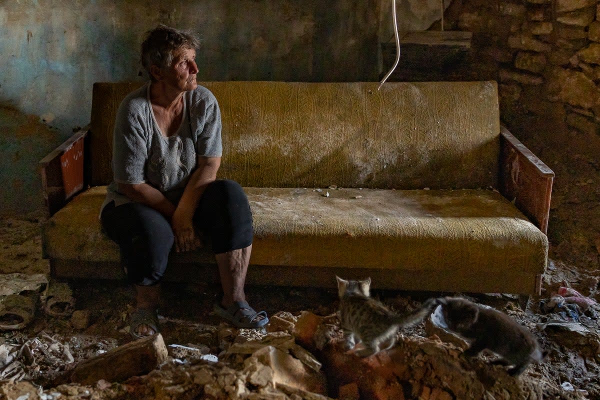 Olha sits by piles of brick which is all that remains of her living room wall in Mykolaiv (Bel Trew)