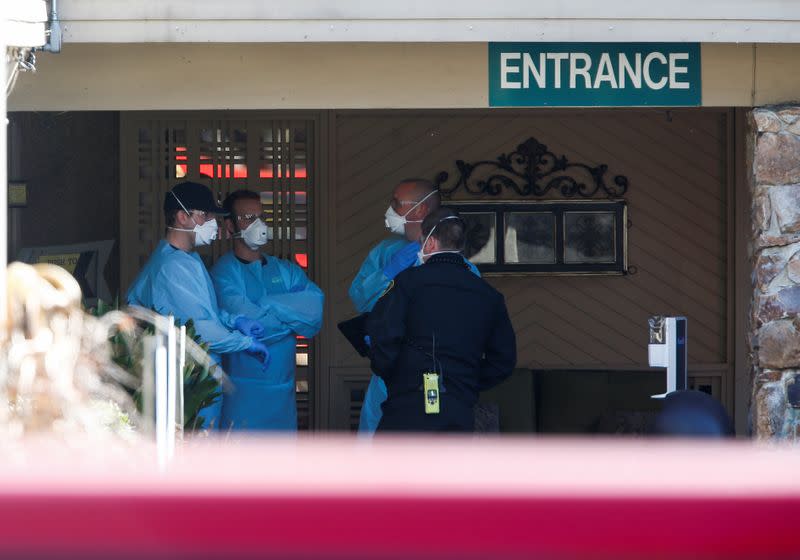 Medics in disposable gowns and masks talk outside the Life Care Center of Kirkland