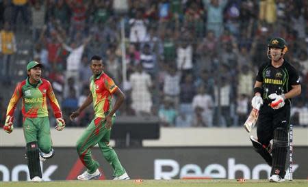 Australia's David Warner leaves the field as Bangladesh's captain Mushfiqur Rahim (L) and bowler Al-Amin Hossain (C) celebrate his dismissal during their ICC Twenty20 World Cup match at the Sher-e-Bangla National Cricket Stadium in Dhaka April 1, 2014. REUTERS/Andrew Biraj