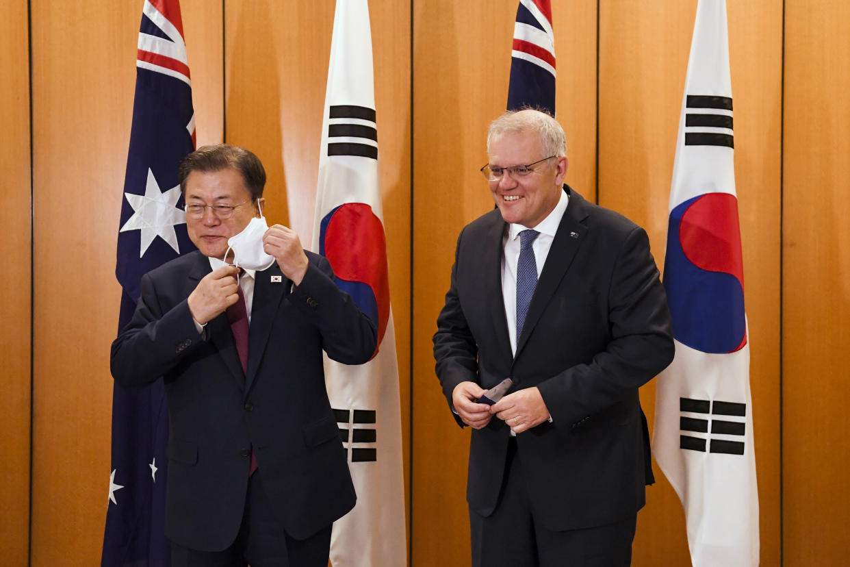 South Korean President Moon Jae-in, left, and Australian Prime Minister Scott Morrison adjust their masks as they pose for a photo at Parliament House, Canberra, Monday, Dec. 13, 2021. Moon is on a two-day official visit to Australia. (Lukas Coch/Pool Photo via AP)