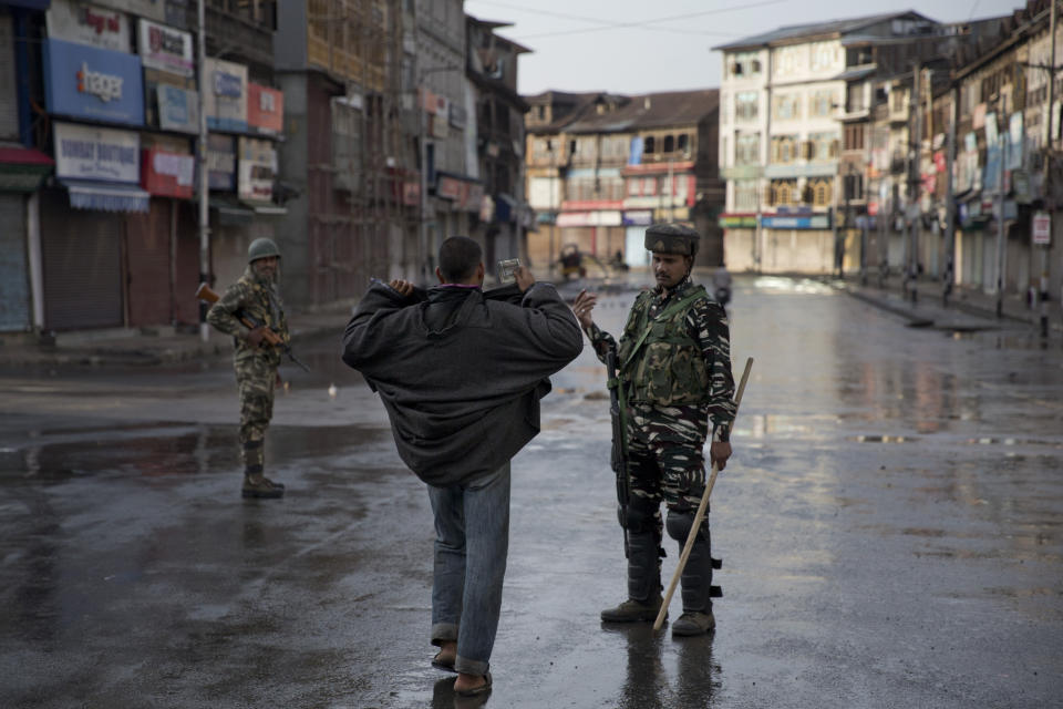 In this Aug. 8, 2019 file photo, an Indian paramilitary soldier orders a Kashmiri to lift his robe before frisking him during curfew in Srinagar, Indian controlled Kashmir. The beautiful Himalayan valley is flooded with soldiers and roadblocks of razor wire. Phone lines are cut, internet connections switched off, politicians arrested. Narendra Modi, the prime minister of the world’s largest democracy has clamped down on Kashmir to near-totalitarian levels. (AP Photo/Dar Yasin, File)